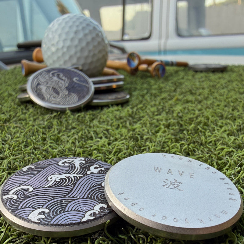 Front and back views of the Wave Nagare stainless steel golf ball marker with an engraved Japanese-inspired wave pattern
