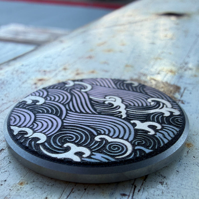 Close-up of the Wave Nagare stainless steel golf ball marker featuring an engraved Japanese-inspired flowing wave pattern