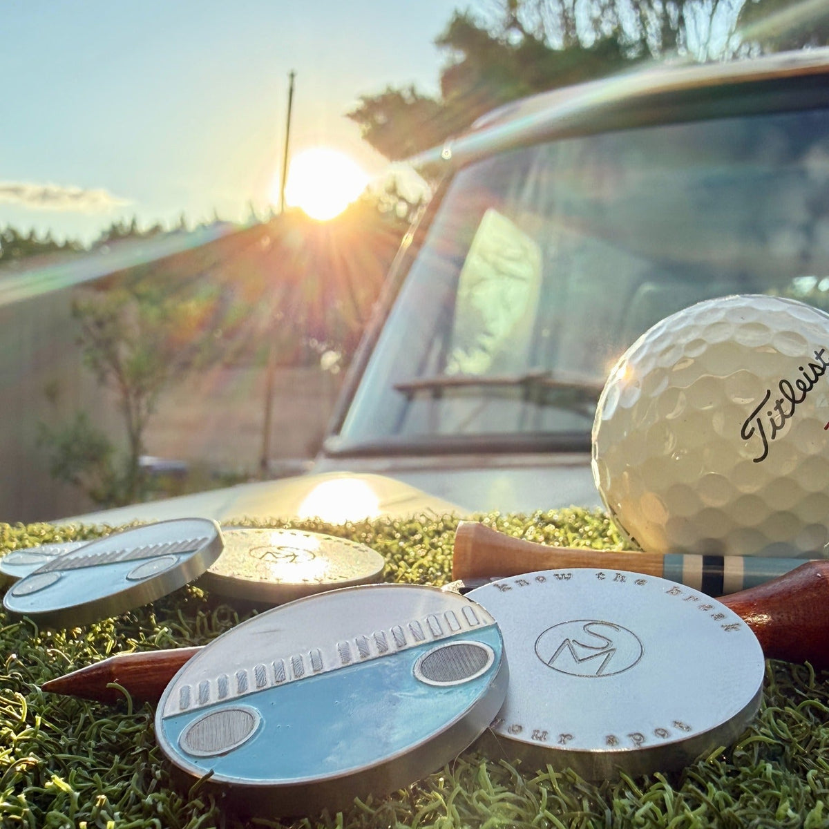 Zissou blue and white enamel golf ball marker shown front and back at sunset beside the 1975 VW Bus
