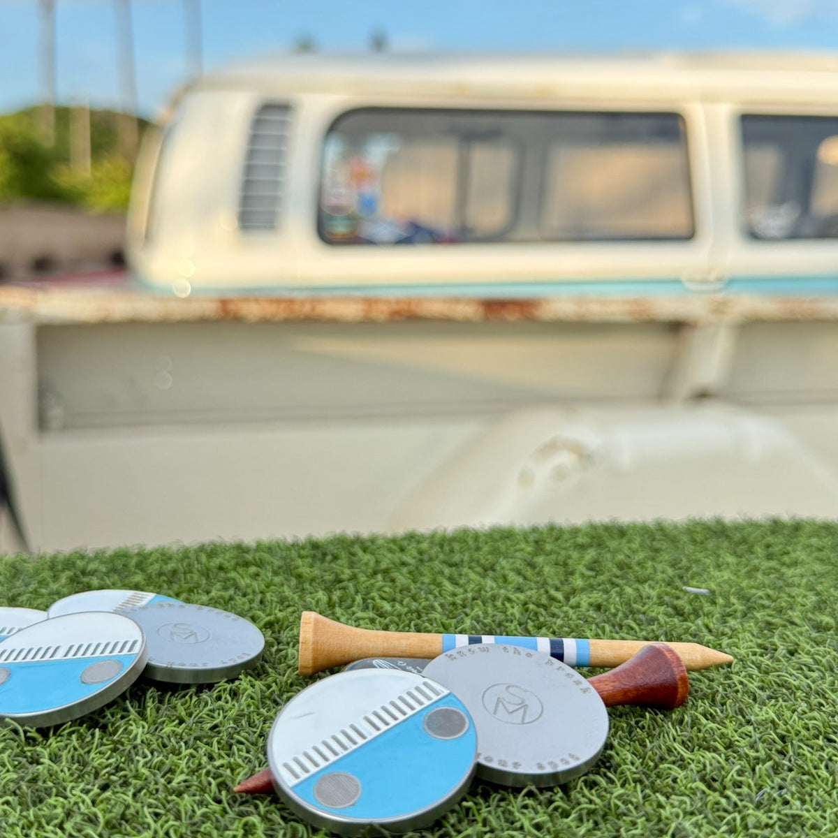 Zissou golf ball marker shown front and back with the blue and white 1975 VW Bus and palm trees in the background